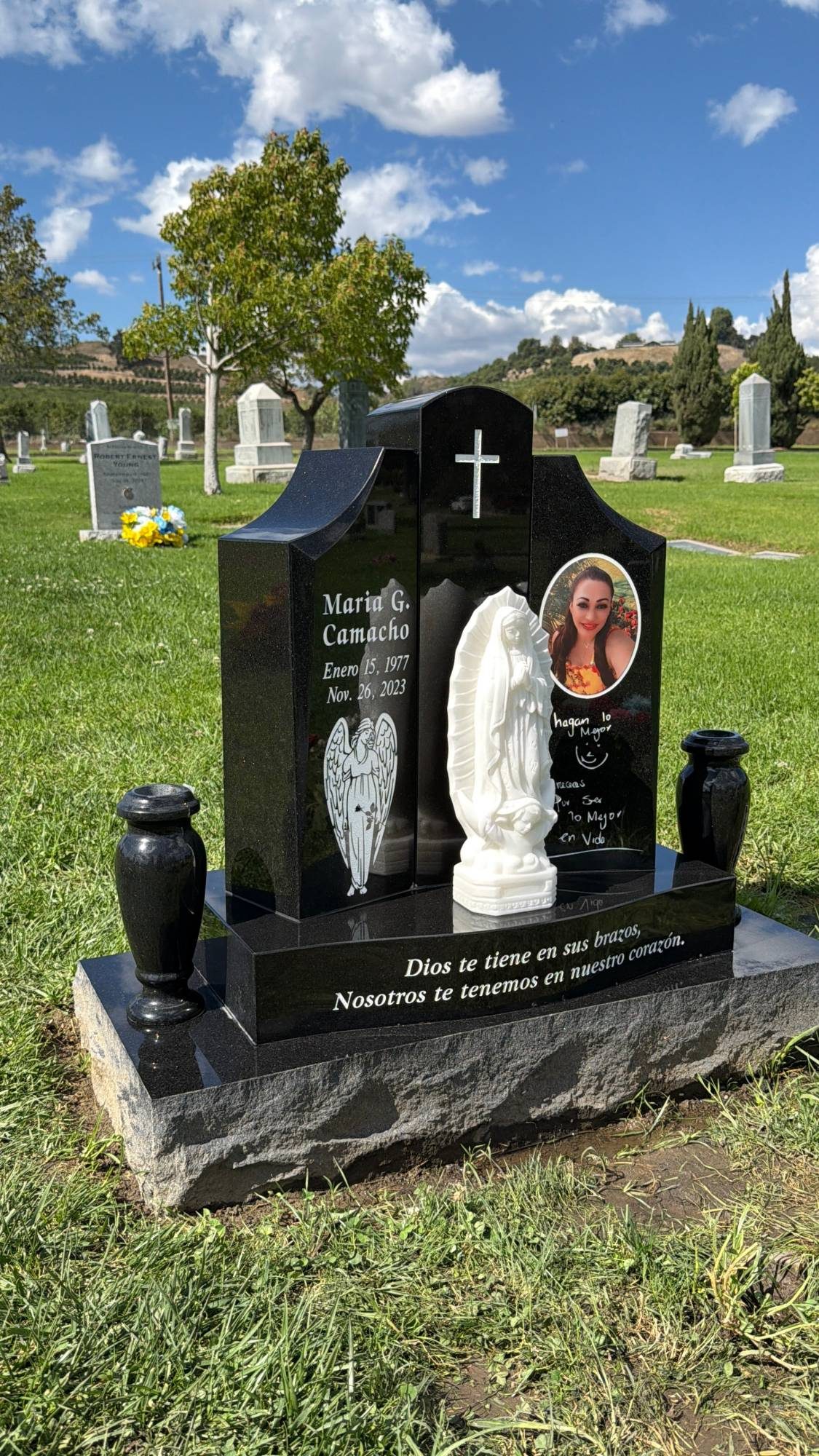 Monumento a la medida con una escultura de mármol de la Virgen de Guadalupe, un retrato y floreros de granito, de GVG Memorials